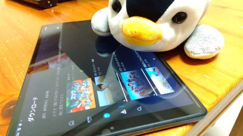 タブレットでAmazonプライムビデオを視聴する子育て中のママと、隣で遊ぶ子どものペンギンのぬいぐるみ