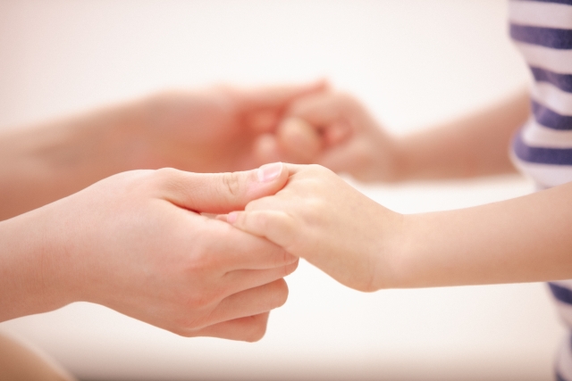 優しく手をつなぐ親子と、ニュースから子どもの心を守る方法についての記事タイトル