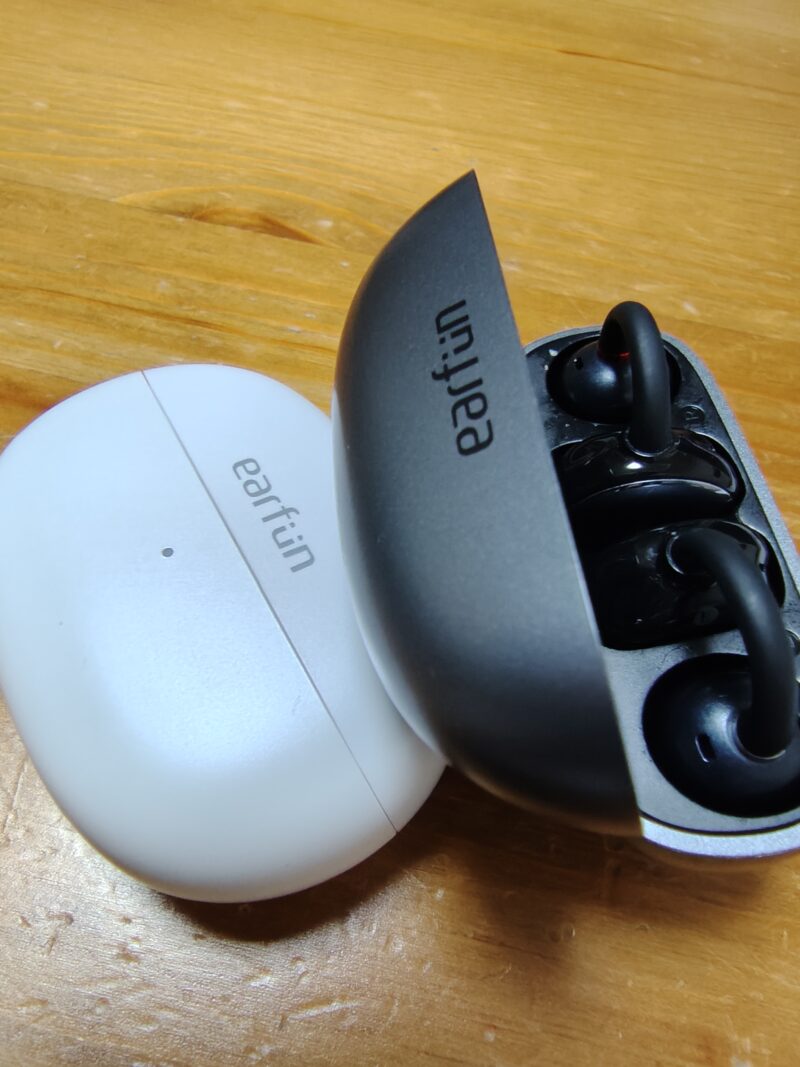 自宅のテーブルに並べられた、夫婦で色違いを愛用しているEarFun Clipの2つのイヤホンの実物写真。